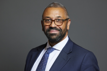 James Cleverly wearing a dark suit jacket with a white shirt and a blue tie with pink dots